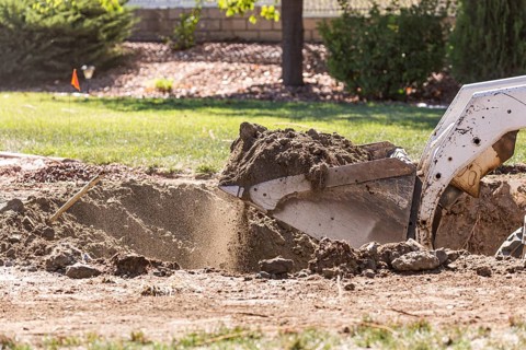 Small bulldozer digging in yard for pool installation