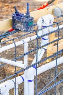 Newly installed PVC plumbing pipes and steel rebar configuration at construction site