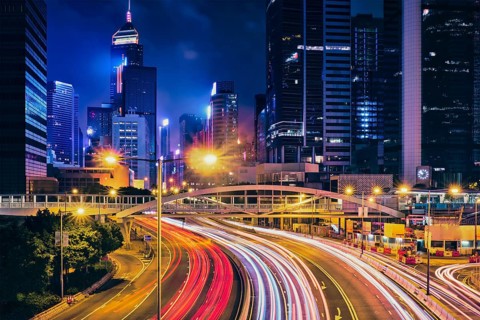 Street traffic in Hong Kong at night. Office skyscraper buildings and busy traffic on highway road with blurred cars light trails. Hong Kong