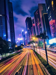 Street traffic in Hong Kong at night. Office skyscraper buildings and busy traffic on highway road with blurred cars light trails. Hong Kong