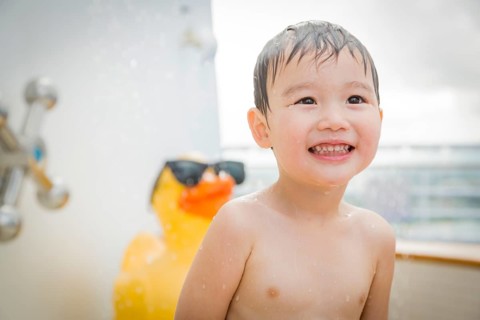 mixed-race boy having fun at the water park with large rubber duck in the background