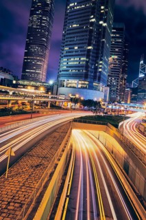 Street traffic in Hong Kong at night. Office skyscraper buildings and busy traffic on highway road with blurred cars light trails. Hong Kong