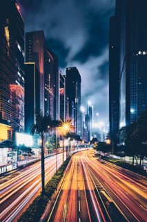 Street traffic in Hong Kong at night. Office skyscraper buildings and busy traffic on highway road with blurred cars light trails. Hong Kong