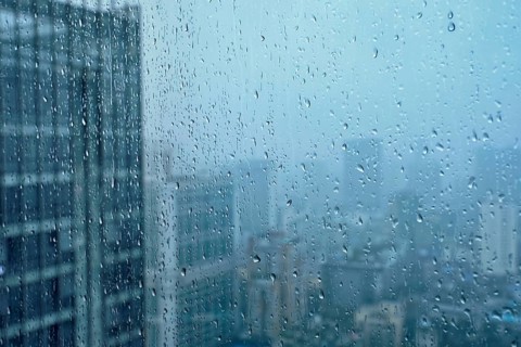 Rain water drops droplets on window glass texture with skyscrapers in background