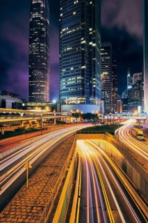 Street traffic in Hong Kong at night. Office skyscraper buildings and busy traffic on highway road with blurred cars light trails. Hong Kong
