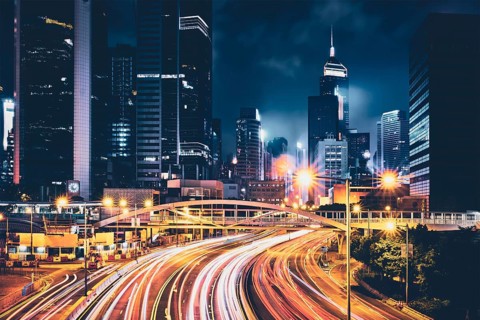 Street traffic in Hong Kong at night. Office skyscraper buildings and busy traffic on highway road with blurred cars light trails. Hong Kong