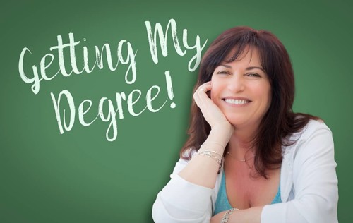 Getting my degree written on green chalkboard behind smiling middle aged woman