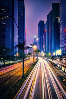 Street traffic in Hong Kong at night. Office skyscraper buildings and busy traffic on highway road with blurred cars light trails. Hong Kong