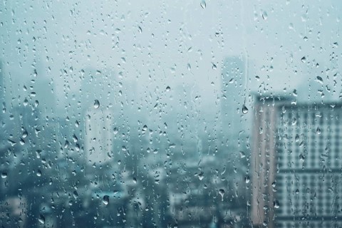 Rain water drops droplets on window glass texture with skyscrapers in background