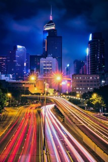 Street traffic in Hong Kong at night. Office skyscraper buildings and busy traffic on highway road with blurred cars light trails. Hong Kong