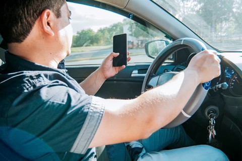 Person holding the cell phone and with the other hand the steering wheel