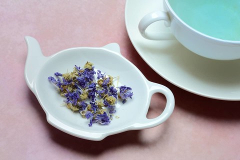 Getrocknete Malvenblueten in Schaelchen und Tasse Malvenbluetentee