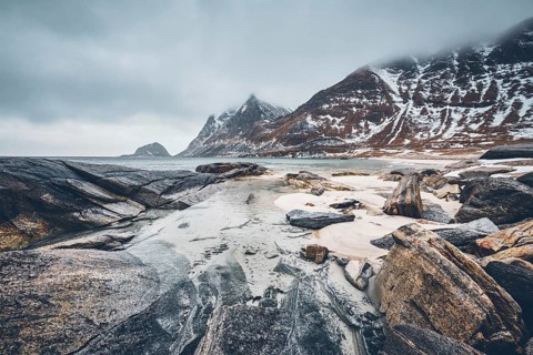 Rocky coast of fjord of Norwegian sea in winter with snow. Haukland beach