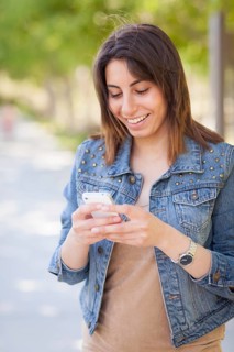 Beautiful young ethnic woman using her smartphone outside