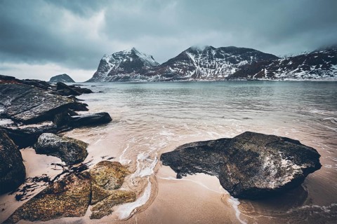 Rocky coast of fjord of Norwegian sea in winter with snow. Haukland beach