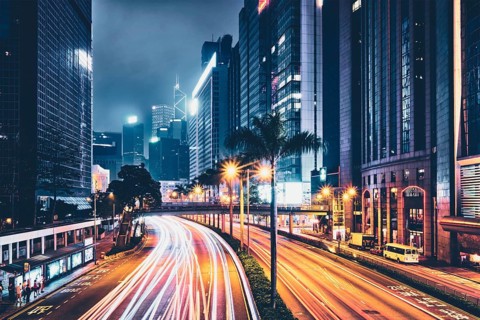 Street traffic in Hong Kong at night. Office skyscraper buildings and busy traffic on highway road with blurred cars light trails. Hong Kong