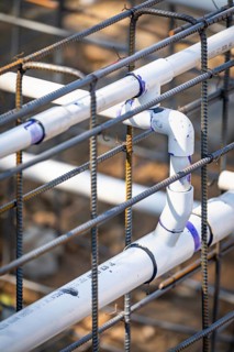 Newly installed PVC plumbing pipes and steel rebar configuration at construction site
