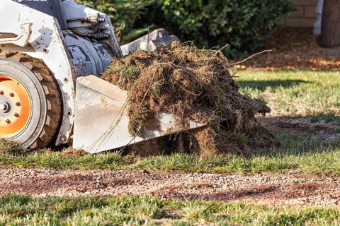 Small bulldozer removing grass from yard preparing for pool installation