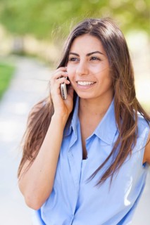 Beautiful young ethnic woman talking on her smartphone outside