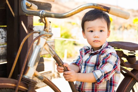 mixed-race caucasian and chinese young boy having fun on the bicycle