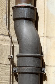 Altes Wasserrohr aus Metall an brauner Mauer