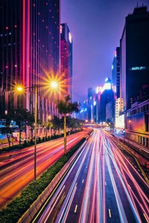 Street traffic in Hong Kong at night. Office skyscraper buildings and busy traffic on highway road with blurred cars light trails. Hong Kong