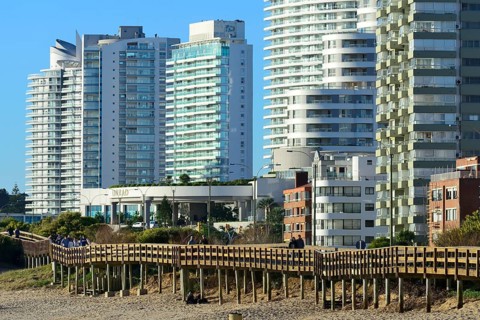 Wooden jetty on the beach in front of high-rise buildings with flats