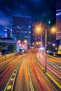 Street traffic in Hong Kong at night. Office skyscraper buildings and busy traffic on highway road with blurred cars light trails. Hong Kong