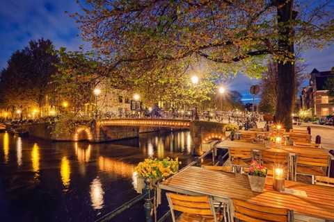 Night view of Amterdam cityscape with cafe tables