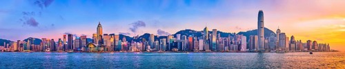 Panorama of Hong Kong skyline cityscape downtown skyscrapers over Victoria Harbour in the evening with junk tourist ferry boat on sunset with dramatic sky. Hong Kong