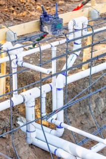 Newly installed PVC plumbing pipes and steel rebar configuration at construction site