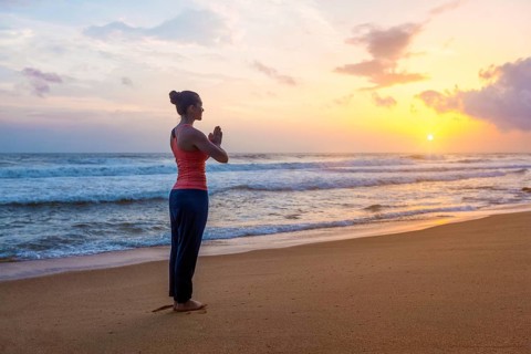 Woman doing Ashtanga Vinyasa Yoga asana Tadasana Samasthiti yoga posture on beach