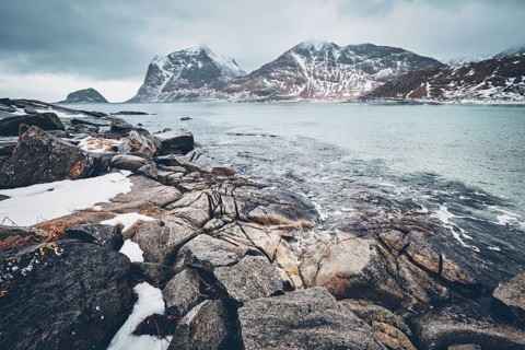 Rocky coast of fjord of Norwegian sea in winter with snow. Haukland beach