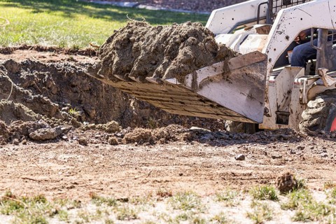 Small bulldozer digging in yard for pool installation