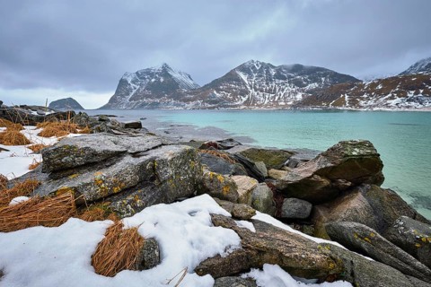 Rocky coast of fjord of Norwegian sea in winter with snow. Haukland beach