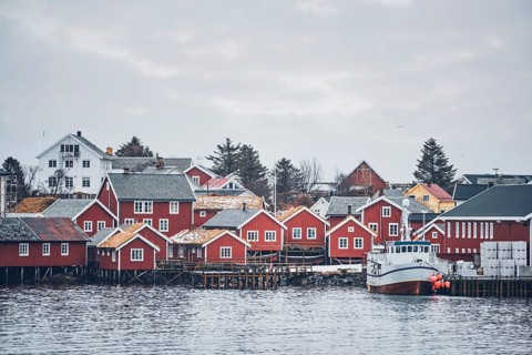 Reine fishing village on Lofoten islands with red rorbu houses in winter with snow with fishing boats. Norway