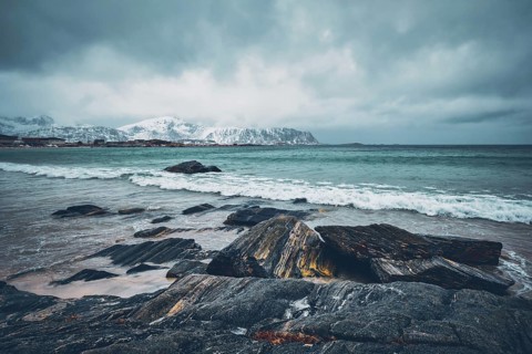 Waves of Norwegian sea on rocky beach of fjord. Ramberg beach