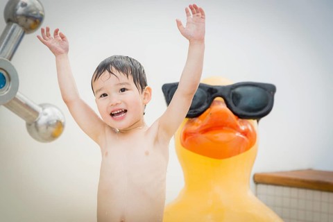mixed-race boy having fun at the water park with large rubber duck in the background