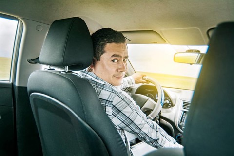 Happy young driver behind the wheel of a car. rear view of a smiling man behind the wheel