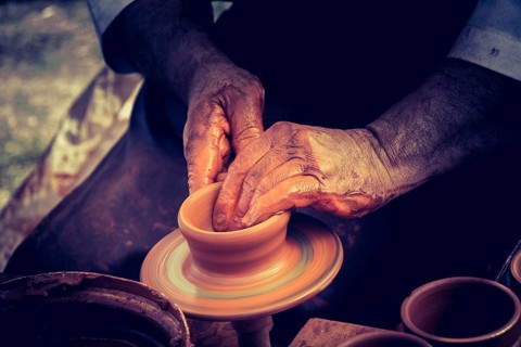 Potter`s hands shaping up the clay of the pot