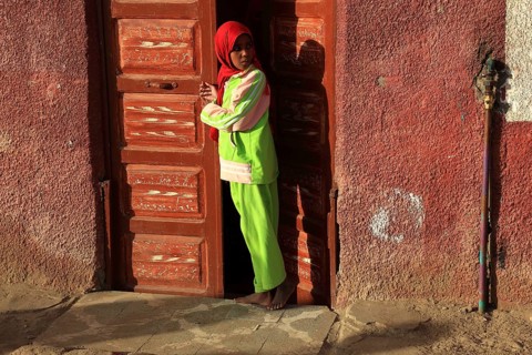 Young girl with headscarf standing in front of the door in a Nubian village in Upper Egypt