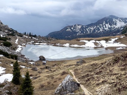 Mountain lake Lago di Valparola with thawing ice surface