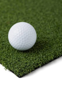 Golf ball resting on section of artificial turf grass on white background