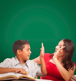 Blank chalk board behind hispanic young boy and famale adult studying
