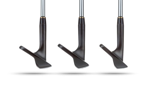 Toes of black golf club wedge irons showing various loft angles of faces on white background