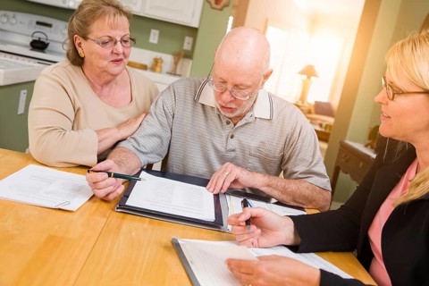 Senior adult couple going over documents in their home with agent at signing