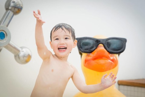 mixed-race boy having fun at the water park with large rubber duck in the background
