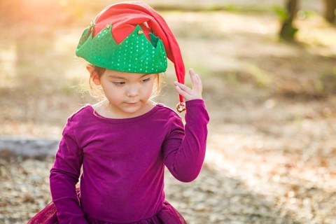 Cute mixed-race young baby girl having fun wearing christmas hat outdoors