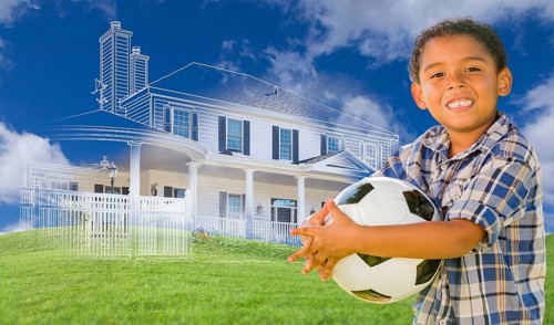 mixed-race young boy holding soccer ball with ghosted house drawing
