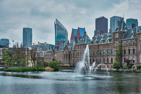 View of the Binnenhof House of Parliament and the Hofvijver lake with downtown skyscrapers in background